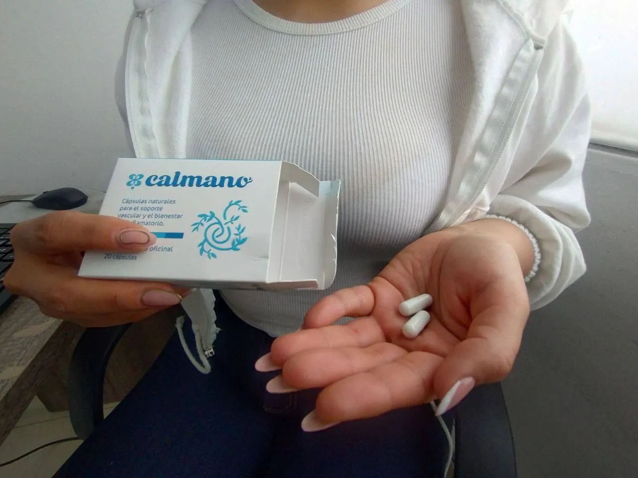 Cápsulas de Calmano en la palma de la mano, junto a la caja de 20, para piernas pesadas y con várices